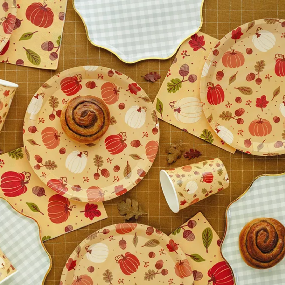 Herfsttafel met papieren bekers, borden en decoratie met pompoenen en bladeren