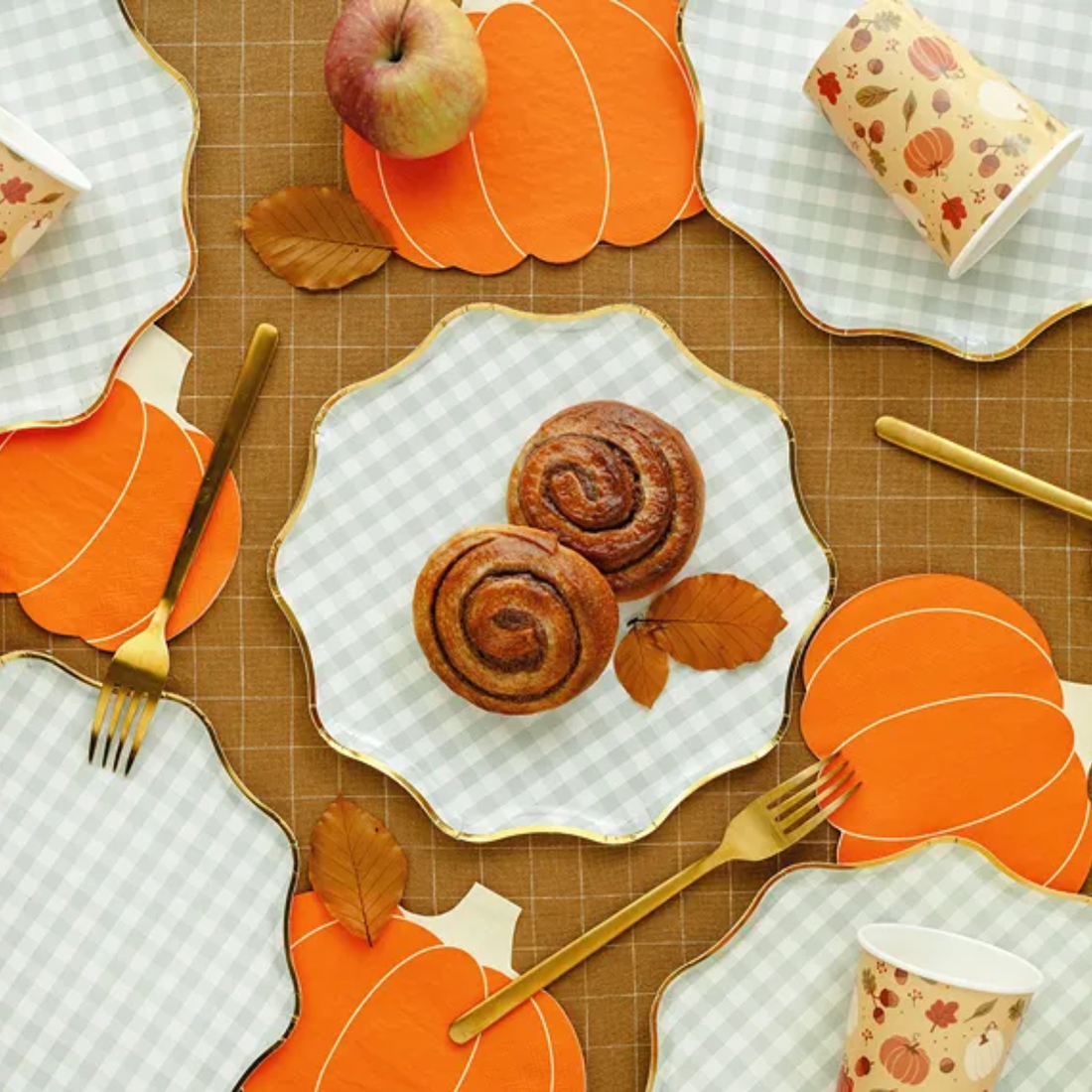 Oranje pompoenservetten op een gedekte herfsttafel met gebak en gouden bestek